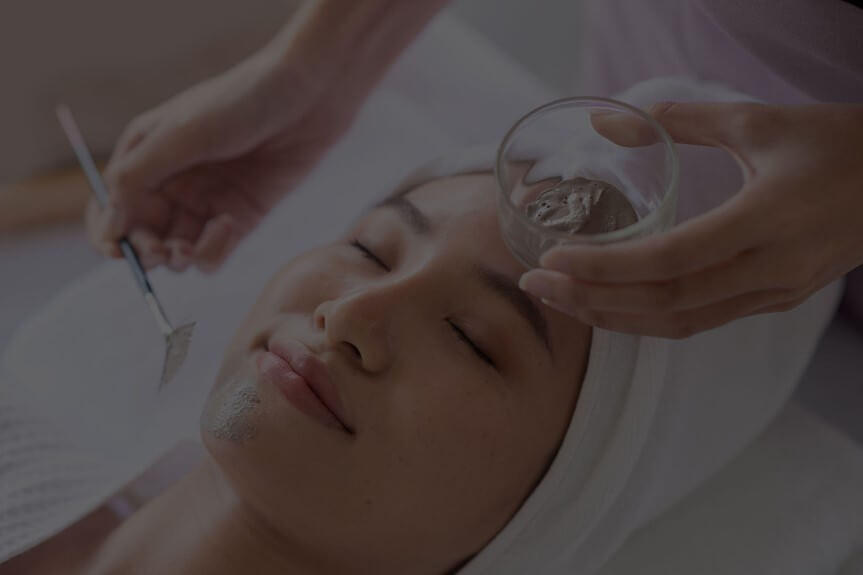 Person lying down with eyes closed, receiving a facial treatment with a precision tool.